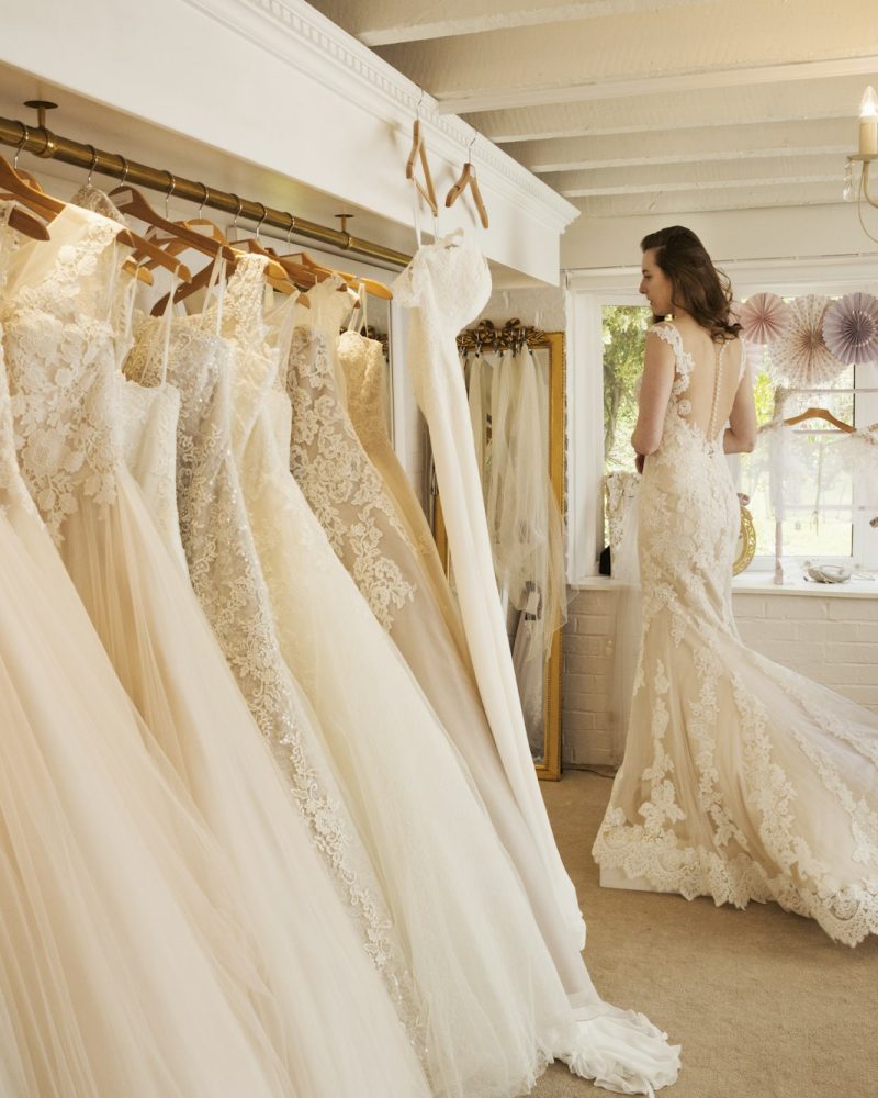 Rows of wedding dresses on display in a specialist wedding dress shop.