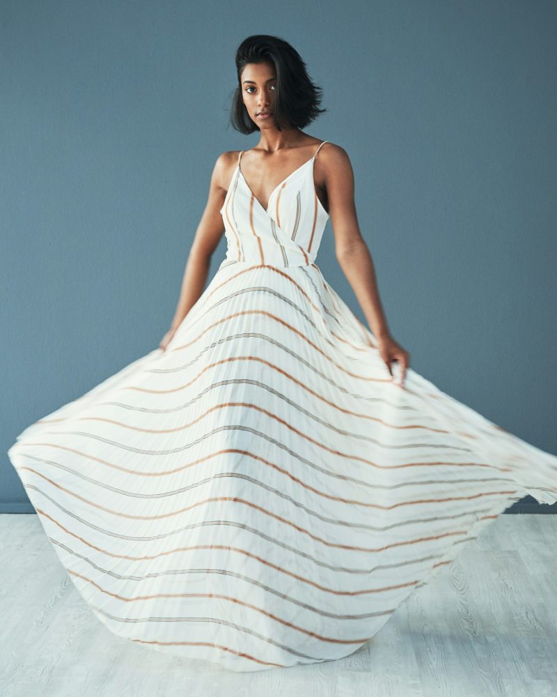 Shot of a beautiful young woman wearing a long flared dress against a blue background